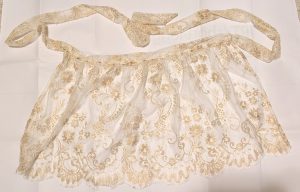 photo of the gold lace apron pinned together on a white paper