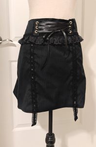 photograph of finished black larme skirt on a mannequin, complete with corset lacing and garter lace straps