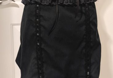 photograph of finished black larme skirt on a mannequin, complete with corset lacing and garter lace straps