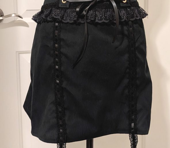 photograph of finished black larme skirt on a mannequin, complete with corset lacing and garter lace straps