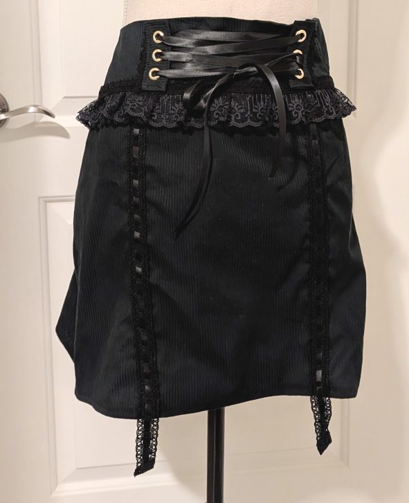 photograph of finished black larme skirt on a mannequin, complete with corset lacing and garter lace straps