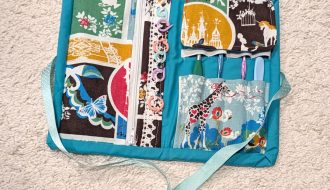 handmade fabric sewn crochet tool kit opened with some hooks and stitch markers displayed
