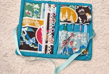 handmade fabric sewn crochet tool kit opened with some hooks and stitch markers displayed