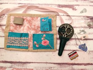 contents of art noveau husswif, with small scissors, pins and needles and safety pins, 2 needle threaders, some thread, thimble, tweezers