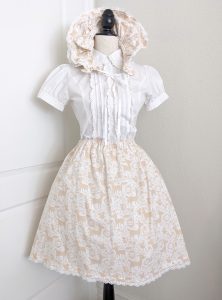 photograph of a beige/white cotton print handmade bonnet and skirt on a mannequin 