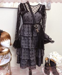 photo of larme-kei outfit on mannequin (circa 2010s) with black sheer polkadot blouse under a grey polkadot slip dress with a black crossbody bag, next to black heel booties and a wig head with a black headband