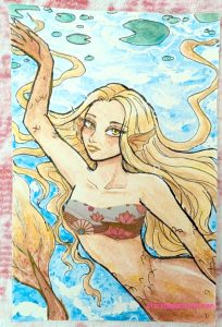 photograph of a mermaid underwater with gold and reddish hair and scales, colored with glitter metallic paints