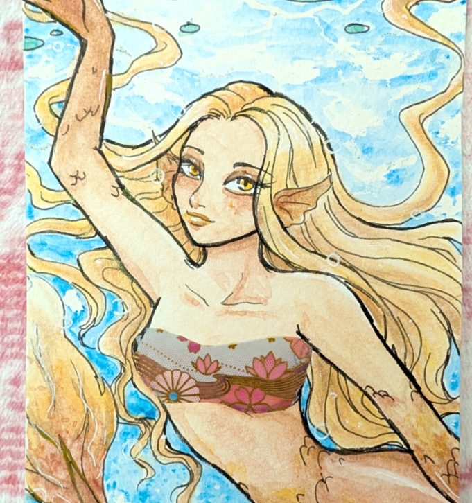 photograph of a mermaid underwater with gold and reddish hair and scales, colored with glitter metallic paints