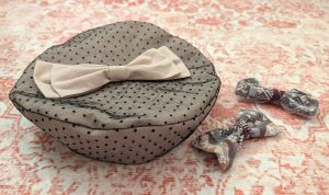 photograph of a handmade fabric beret sewn from pink fabric overlaid with black polkadot lace and decorated with a pink fabric bow, next to two purple/pink/white Japanese print bows