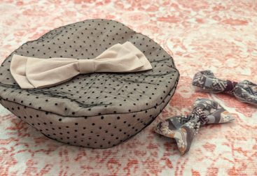 photograph of a handmade fabric beret sewn from pink fabric overlaid with black polkadot lace and decorated with a pink fabric bow, next to two purple/pink/white Japanese print bows