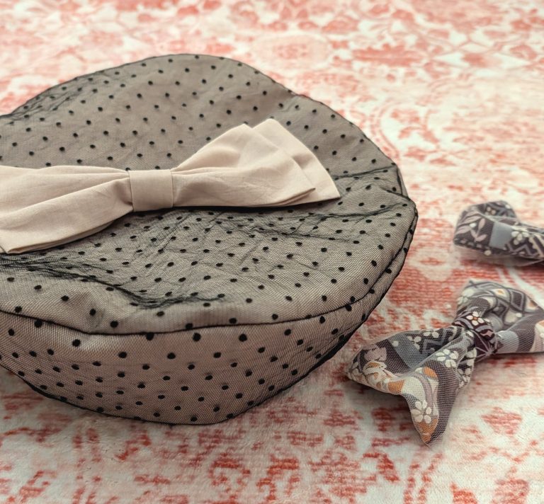 photograph of a handmade fabric beret sewn from pink fabric overlaid with black polkadot lace and decorated with a pink fabric bow, next to two purple/pink/white Japanese print bows