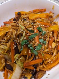 photo of egg/wheat noodles in sauce with stir fry veggies and scramble egg and a bit of chopped basil