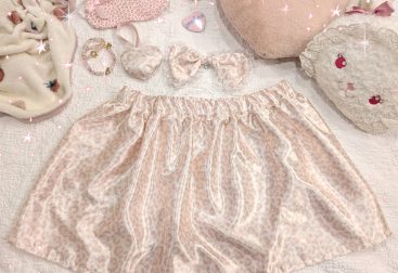 photograph of pink/white satin leopard print skirt with matching bow and heart ornament, surrounded by other cute pink items