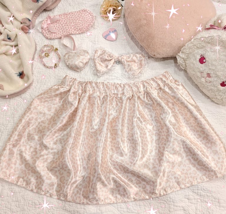 photograph of pink/white satin leopard print skirt with matching bow and heart ornament, surrounded by other cute pink items
