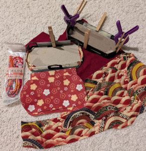 reconstruction of a broken PSP case with Japanese printed red cotton, Japanese printed red felt, and a Japanese print red cord, along with dark red felt. Also bits of plastic from Daiso, lots of wood glue, clamps and clothespins