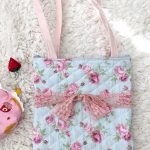 photograph of a blue/pink floral print tote bag with a pink lace bow