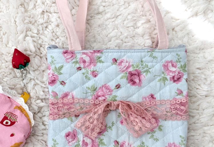 photograph of a blue/pink floral print tote bag with a pink lace bow