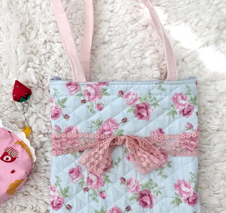 photograph of a blue/pink floral print tote bag with a pink lace bow