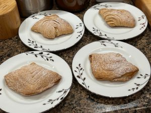 photo of four very homemade sfogliatelle Italian pastries covered with powdered sugar