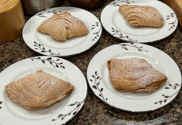 photo of four very homemade sfogliatelle Italian pastries covered with powdered sugar