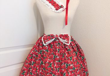 photo of handmade ruffle skirt, lace-trimmed bow, lace trimmed headdress and lacy scrunchies from a bright red strawberry print cotton fabric