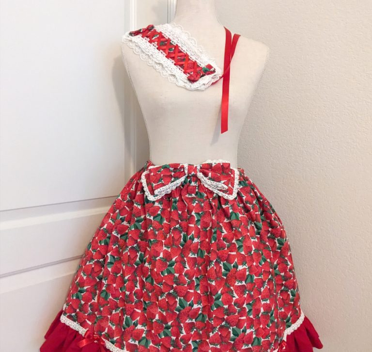 photo of handmade ruffle skirt, lace-trimmed bow, lace trimmed headdress and lacy scrunchies from a bright red strawberry print cotton fabric