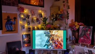 photograph of PC setup featuring pink Razer accessories and Final Fantasy Tactics, 7 and 9 official and fan merch. with the main light turned off
