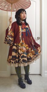 photo of myself in CEL"Kaiseki in Waves" wa-lolita jumperskirt and haori holding a red paper parasol, looking off into the distance