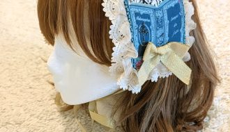 photograph of handmade headdress trimmed with lace and ribbons on a wig head wearing a brown wig